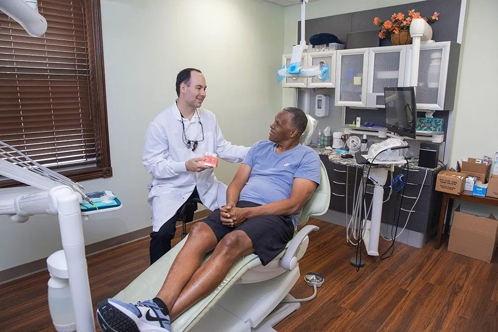 Dr. Nakhla showing a relaxed patient a tooth model in a real Independence Family Dentistry operatory