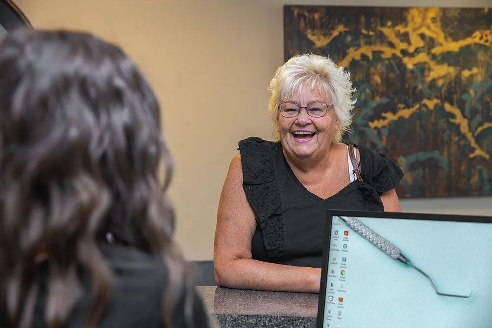A patient laughing with a team member at the front desk